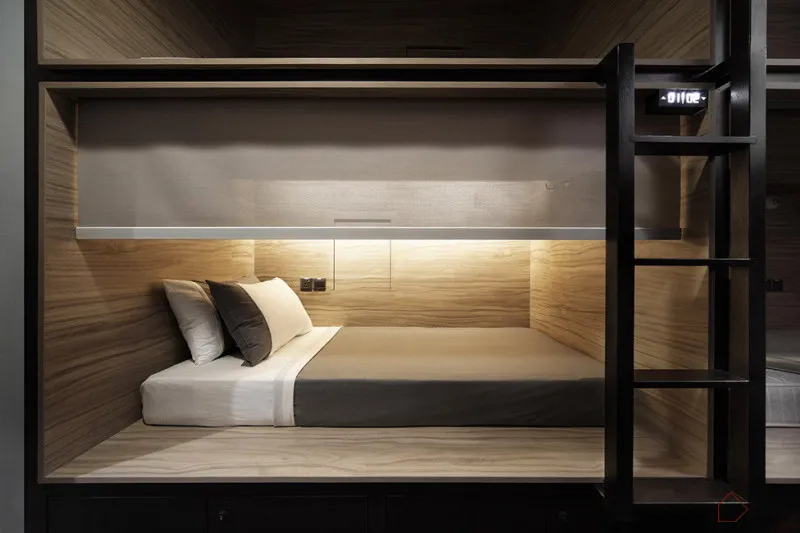 A minimalist bedroom with a wooden platform bed, white bedding, and black and white pillows.