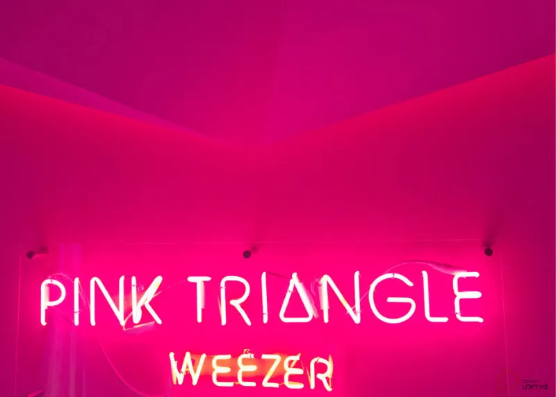 粉紅色霓虹燈招牌,寫有「Pink Triangle」與「Weezer」小寫字母。