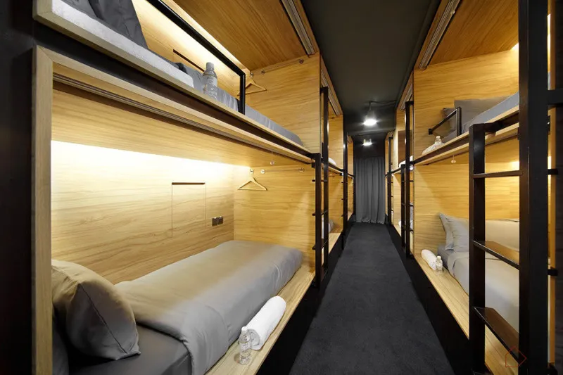 A modern bedroom with wooden bunk beds, grey bedding, and black carpet.