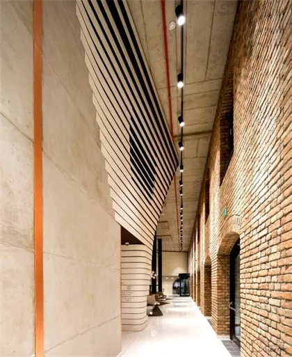 Modern architectural design featuring brick walls, concrete columns, and vertical blinds in a corridor.