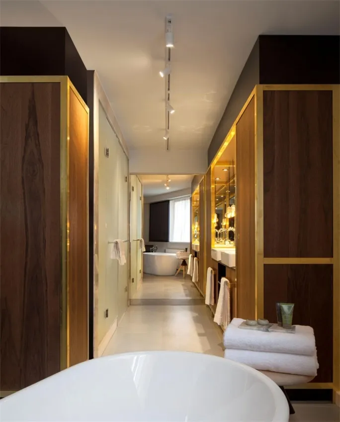 A modern bathroom suite featuring a freestanding bathtub, wooden cabinets, and glass elements.
