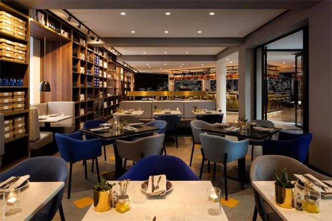 Modern restaurant interior with concrete finish, featuring contemporary furniture and a bar counter.