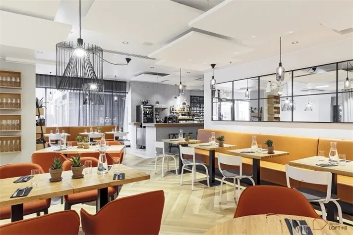 A modern restaurant interior with wood tables, chairs, and flooring.