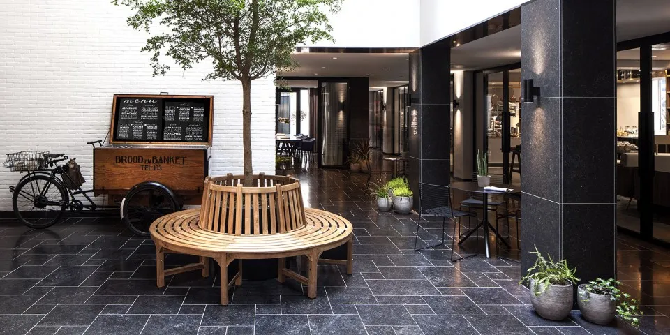 現代餐廳室內,配有木製座椅、水泥地板,以及盆栽植物作為裝飾。