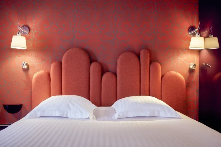 Modern bedroom with an orange upholstered headboard and white bedding.