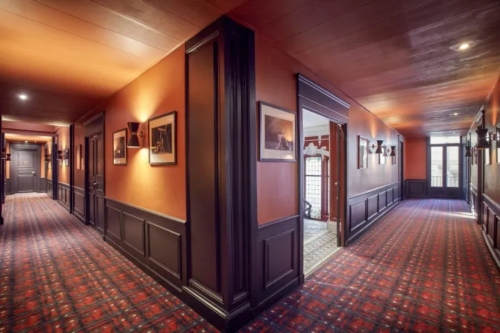 Interior design featuring a carpeted hallway with wood-paneled walls.