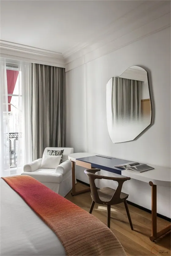 A modern bedroom with white curtains and a wooden floor.