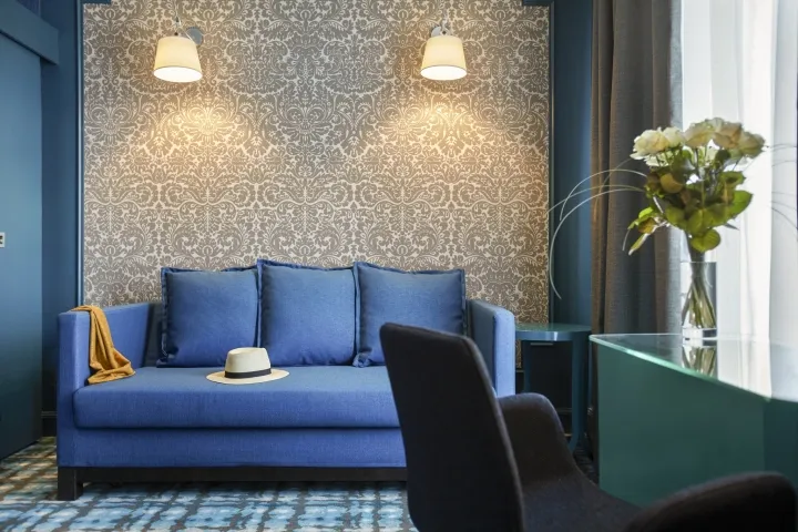 A modern living room with a blue sofa and patterned wallpaper