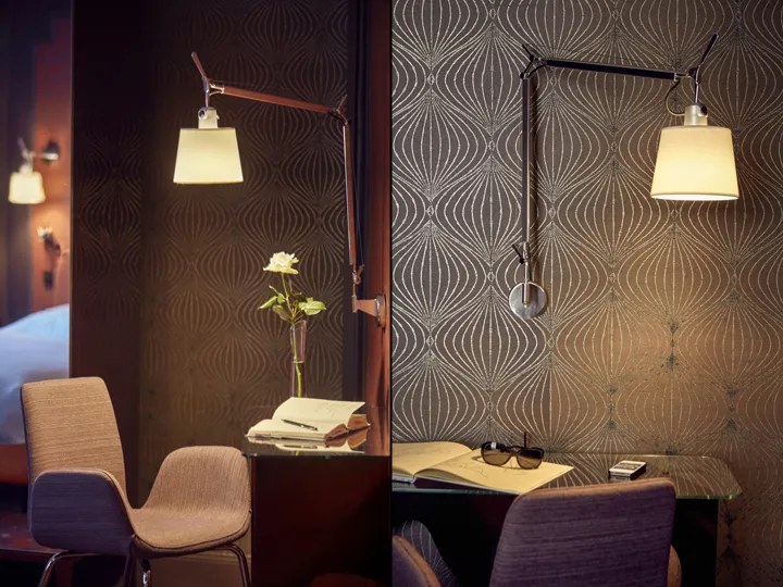 A modern home office setup featuring a metal desk with a vase of flowers, a book, and sunglasses.