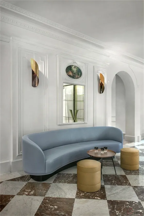 A modern industrial living room featuring metallic furniture, modern decor, and a curved sofa with a geometric coffee table a