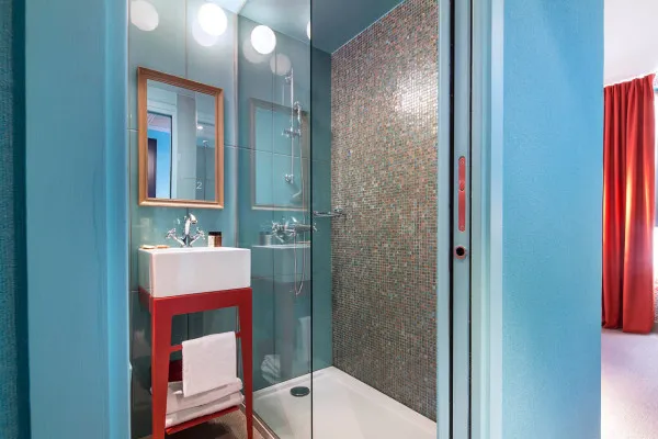 A modern bathroom featuring blue tiled walls and a glass shower enclosure.