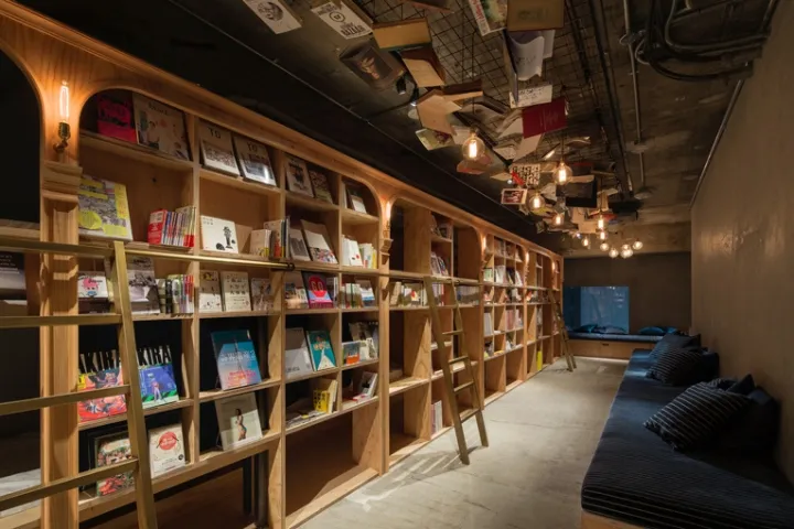 A modern industrial library with wooden shelves and hanging lamps, providing a comfortable and cozy reading environment with