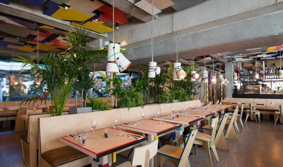 現代工業風餐廳室內,採用混凝土地板、木質家具與綠色植物。