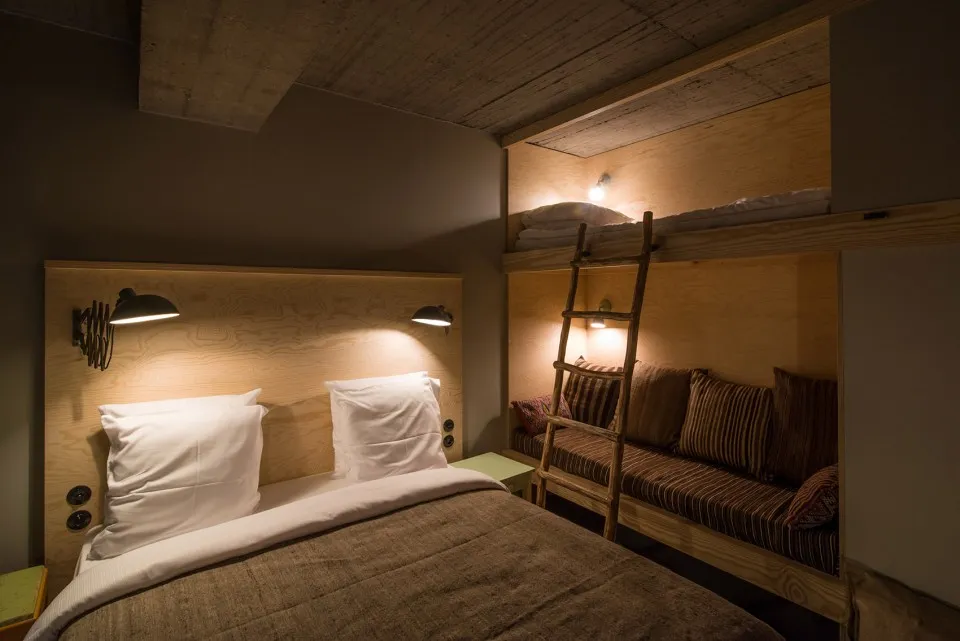 A minimalist bedroom with wooden furniture and a bunk bed with a ladder.