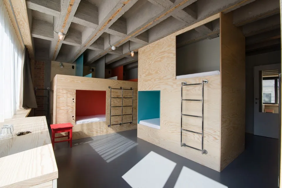 Modern minimalist bedroom with wooden bunk beds and red accents