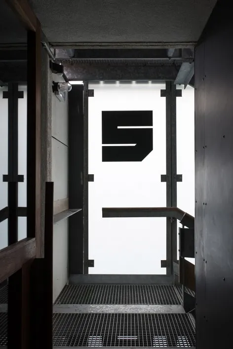 Modern minimalist metal interior with a large black 'S' logo and grid floor