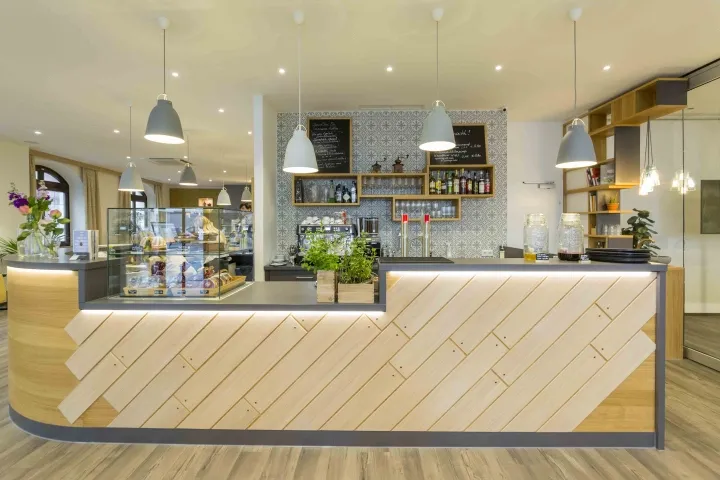 A modern coffee shop with a wooden counter bar, glass display cases, and potted plants.