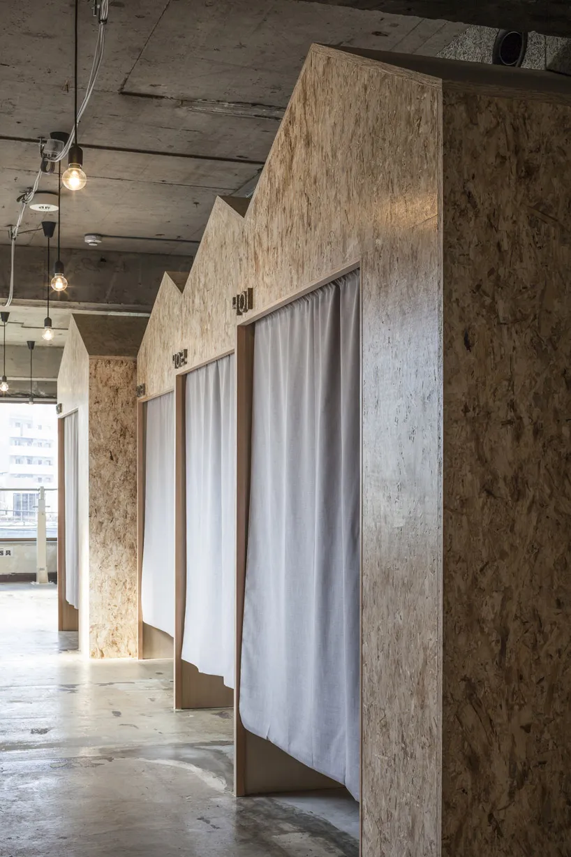 Minimalist architectural showroom with wooden structures, white curtains, and a concrete floor.