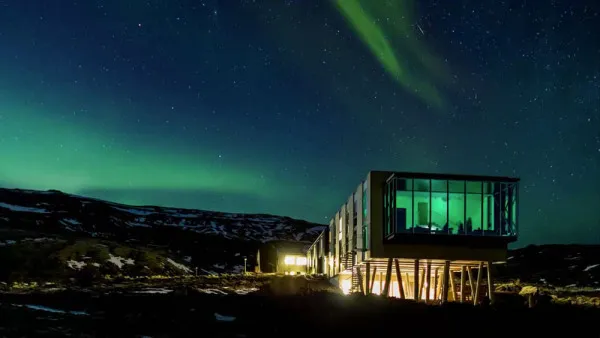 A modern house with a glass extension and green lights in the sky.