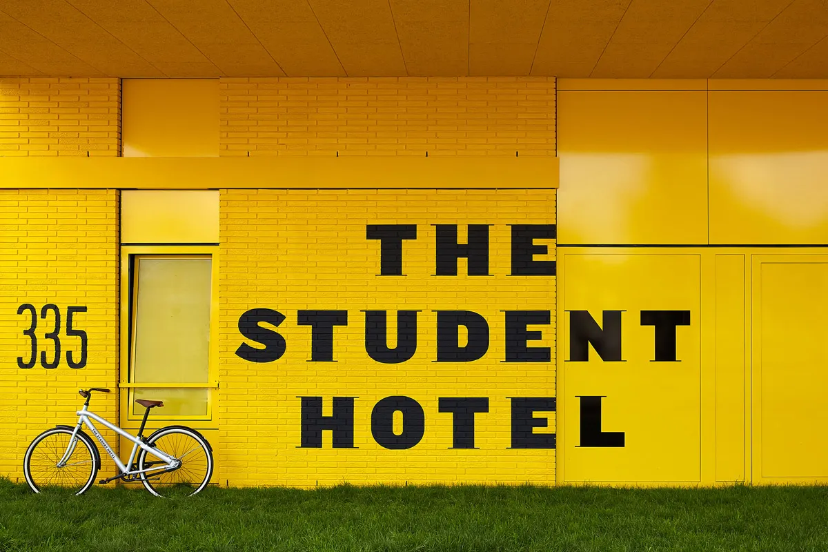 黃磚建築牆面漆有「The Student Hotel」字樣,前面停放一輛白色自行車。