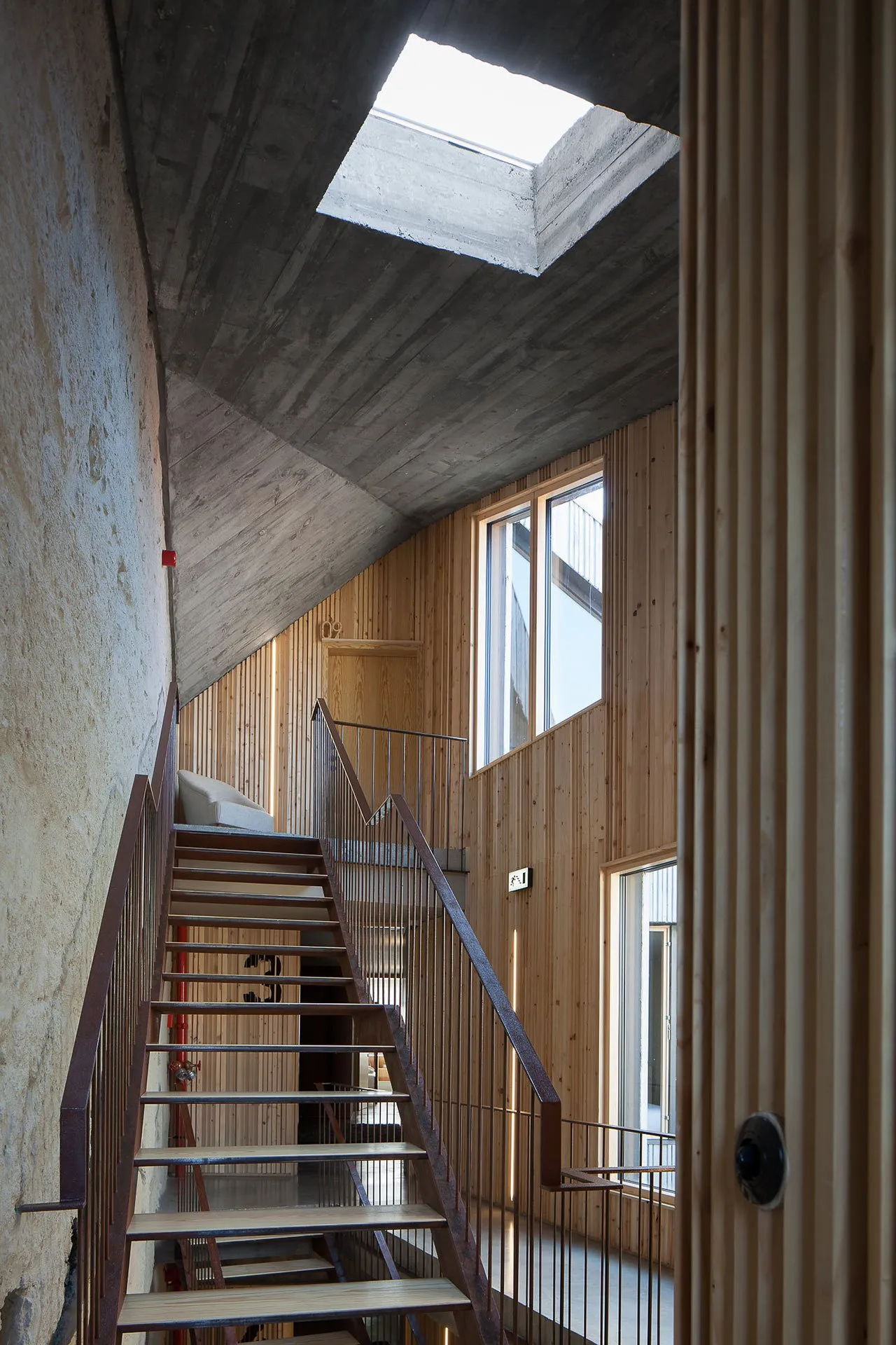 Industrial-style home interior with wood and concrete walls, concrete ceiling, and steel staircase.
