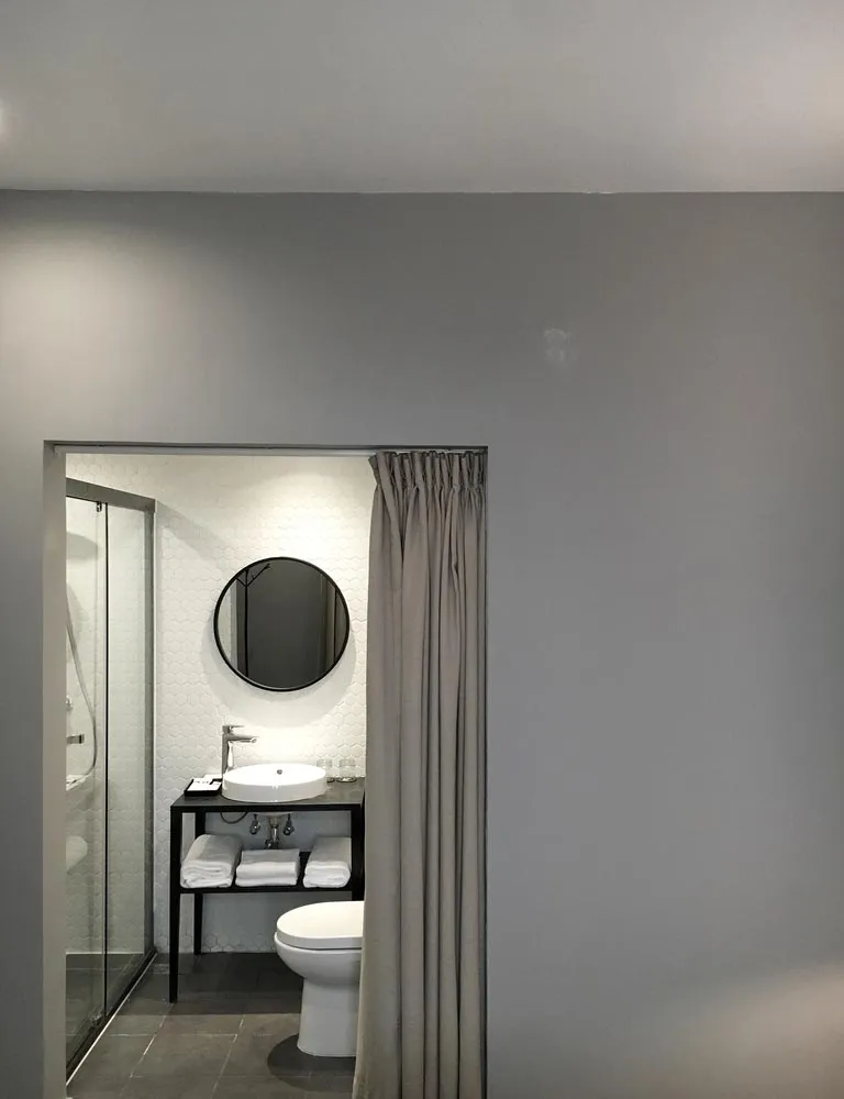 Modern minimalist bathroom with white tile walls, a glass shower door, and a sleek metallic sink.