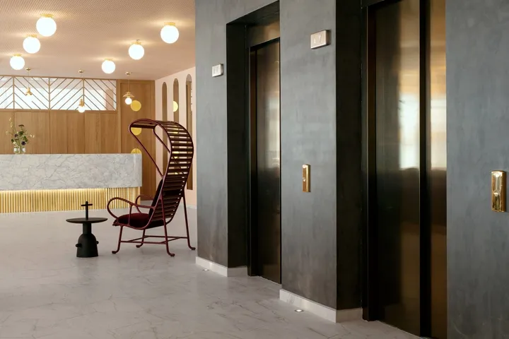 Modern hotel lobby featuring concrete, marble, metal, glass, and wooden finishes.