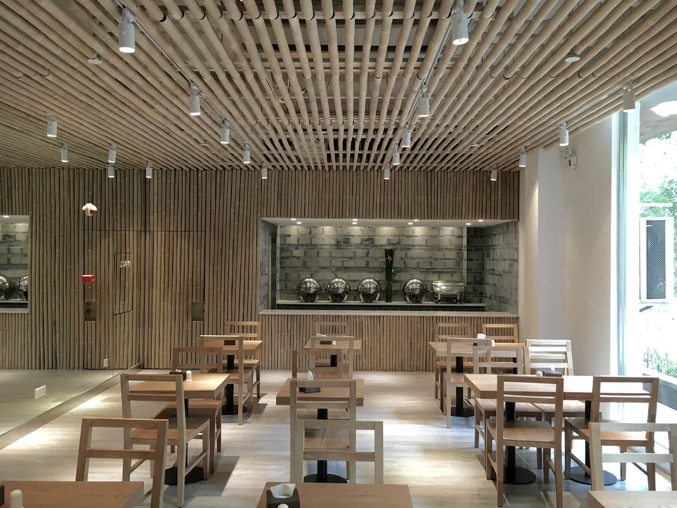 一間現代餐廳,配有木質餐桌、餐椅與天花板。特色包含木質牆面與地板,以及不鏽鋼元素。