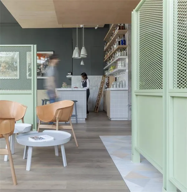 A cozy, modern restaurant/cafe interior with a light gray wooden floor, white walls, and various design elements like pendant