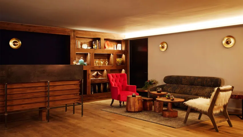 A modern living room with wood floors, a red armchair, a wooden coffee table, and a wooden cabinet with shelves.