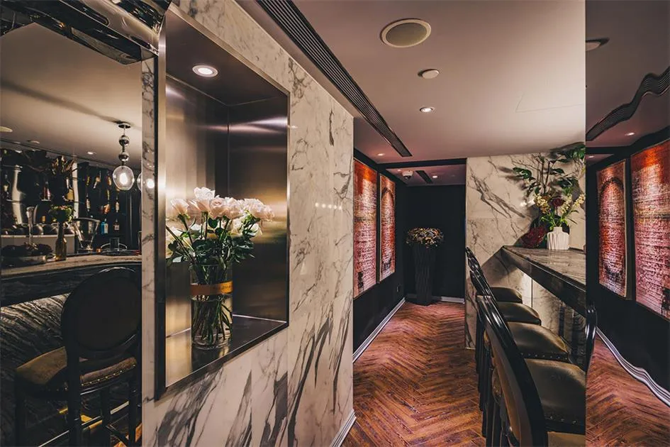 A stylish bar area with marble walls and a wooden floor.