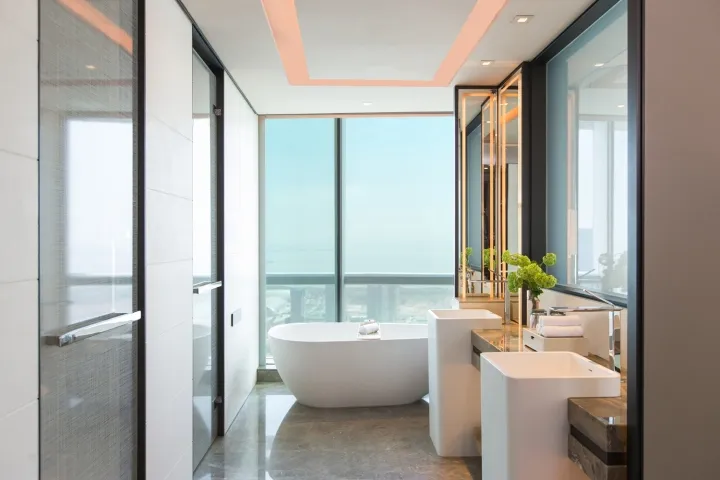 A modern bathroom featuring a white marble tub, sinks, and a glass enclosed shower.