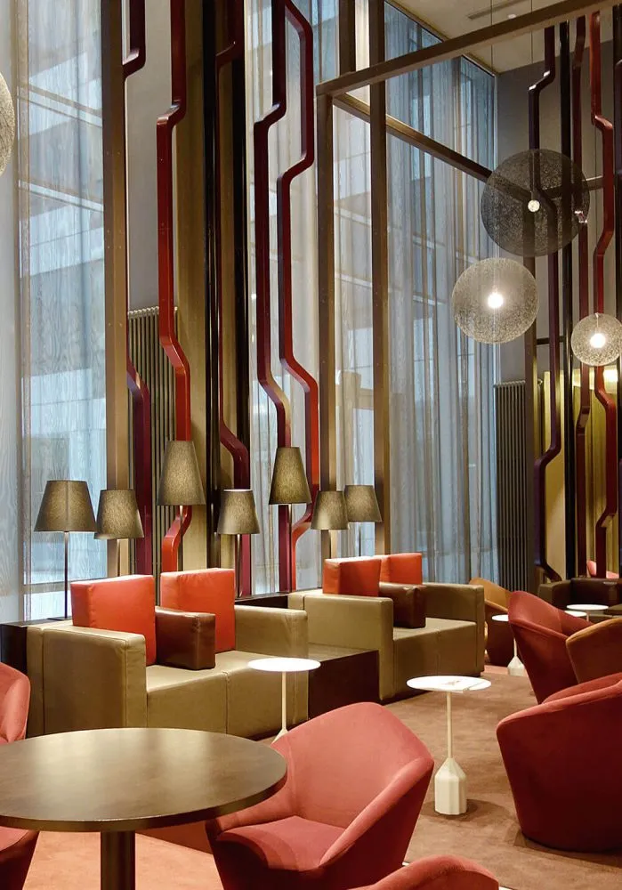 A modern hotel lobby featuring a basketweave marble floor and red chairs