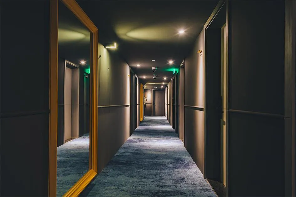 現代酒店內的長走廊,鋪設地毯並搭配嵌入式照明。