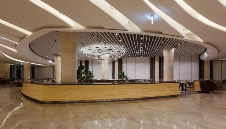 Modern hotel reception with marble circular ceiling panel and wooden counter.