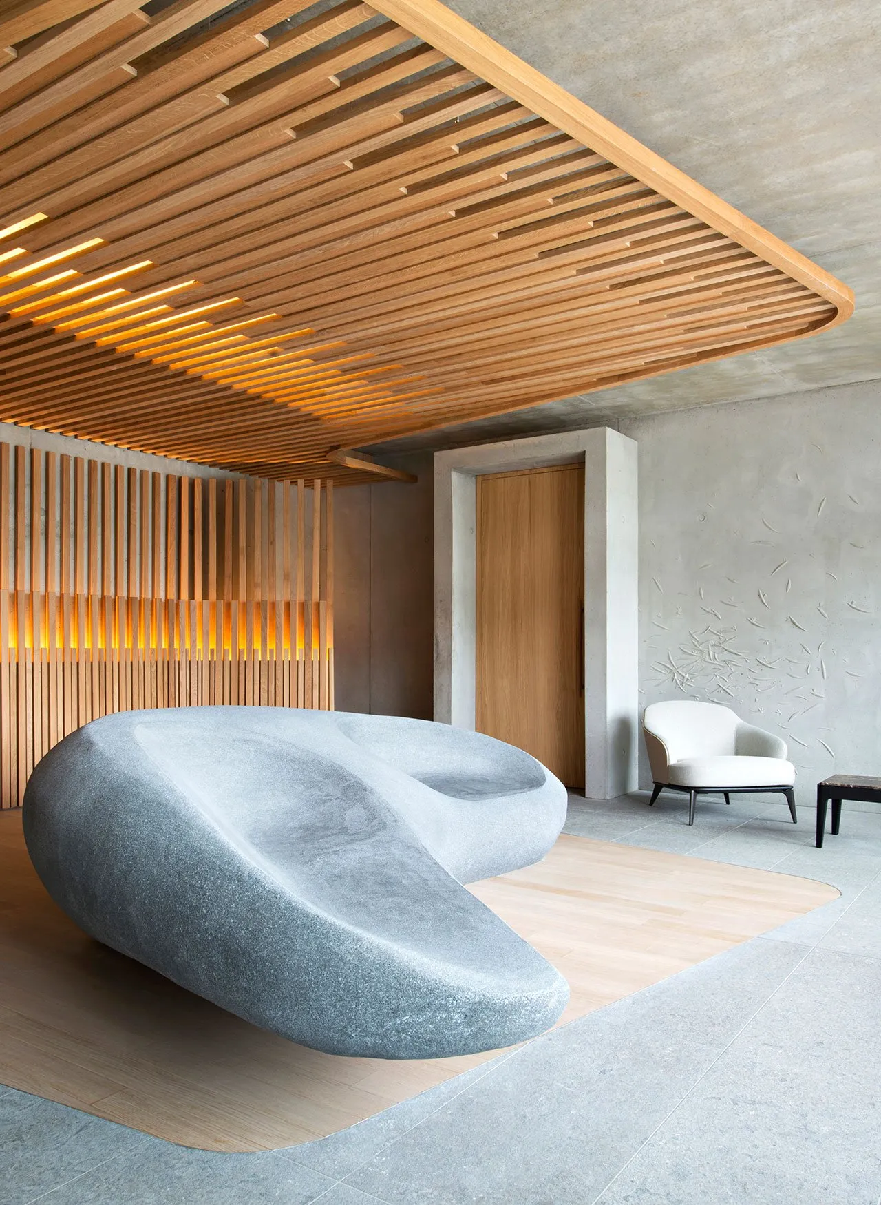 Modern living room with marble sofa, concrete wall, and wooden accents