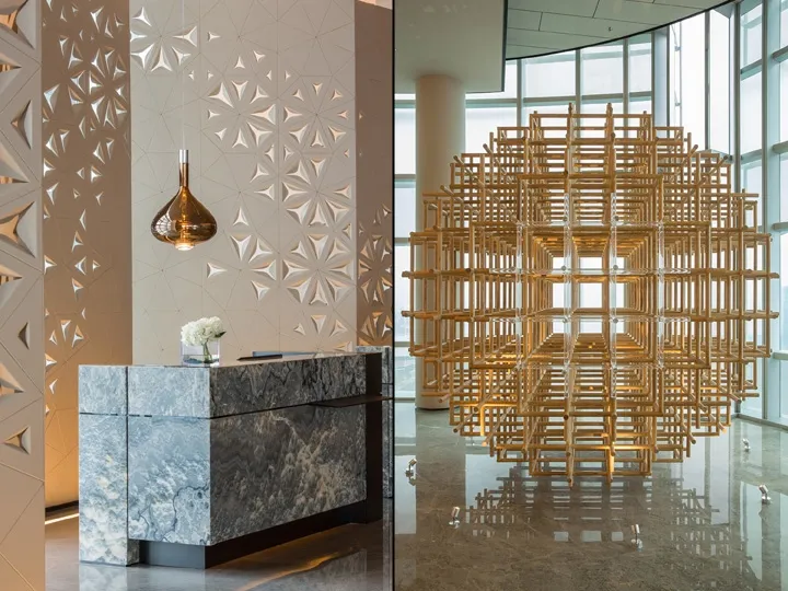 A modern reception desk with a marble surface and intricate wall design.