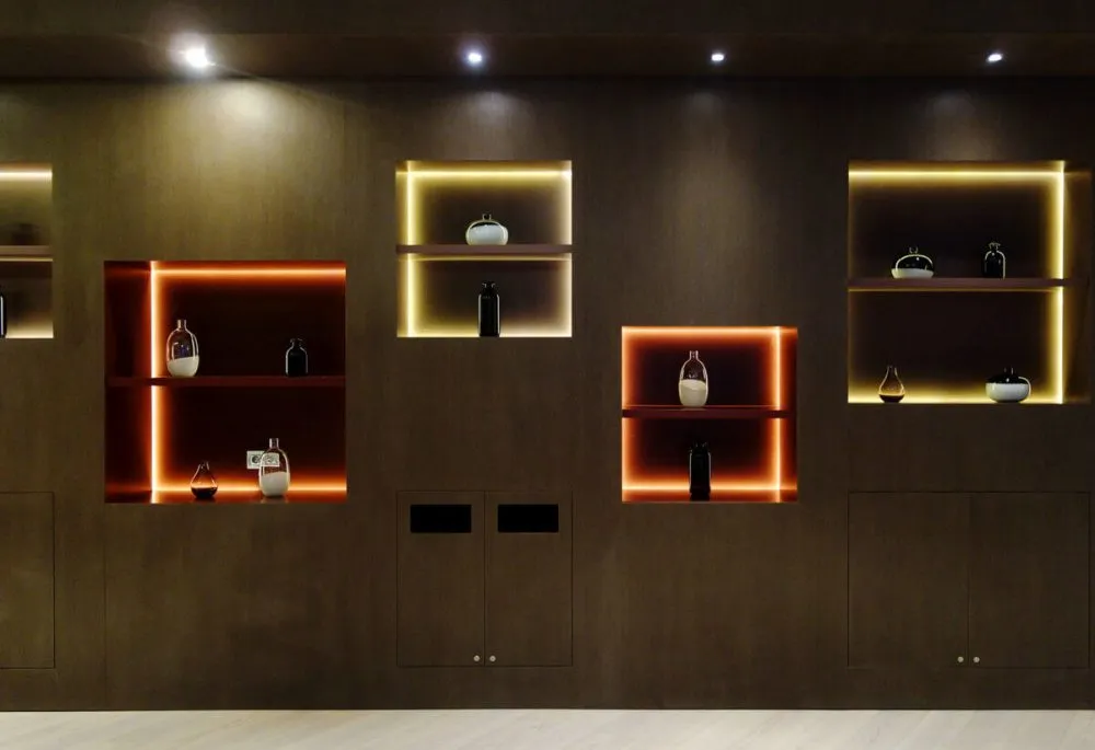 Wall-mounted wooden shelves with integrated lighting in a minimalist interior design setting.