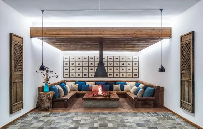 A modern industrial living room with a cozy fireplace, sectional sofa, and overhead lighting.