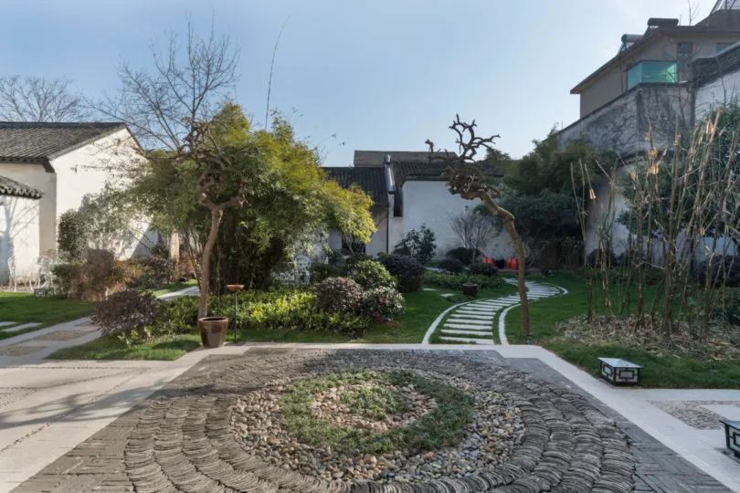 A serene garden featuring natural stones, grass, and trees.