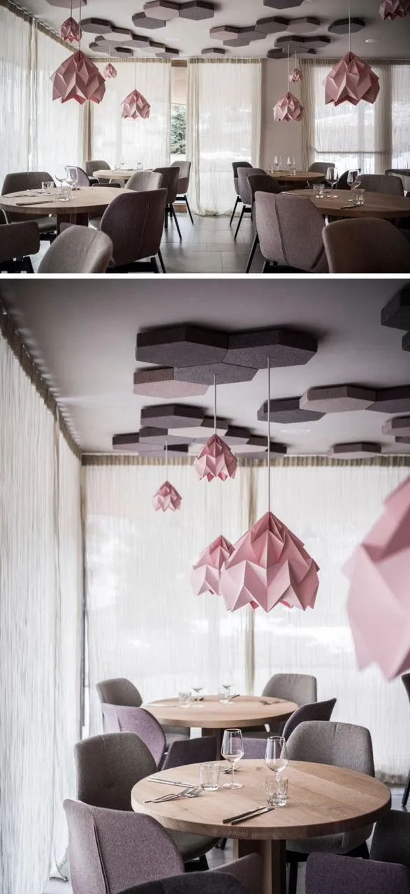 A minimalist restaurant interior featuring modern, geometric paper light fixtures hanging from the ceiling.