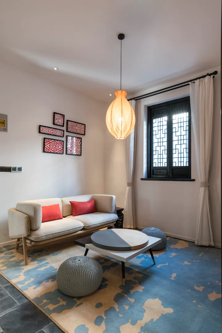A modern living room with a geometric patterned rug, a white modular sofa with red throw pillows, and a round coffee table wi