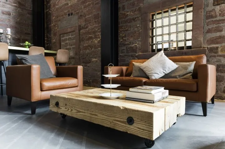 A cozy industrial living room with leather furniture, wooden coffee table, and brick walls