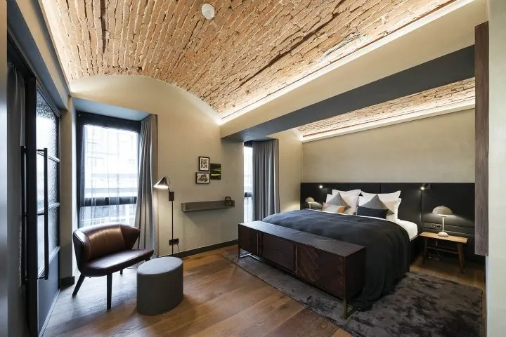A bedroom with a rustic brick ceiling, wooden floors, and industrial-style decor.