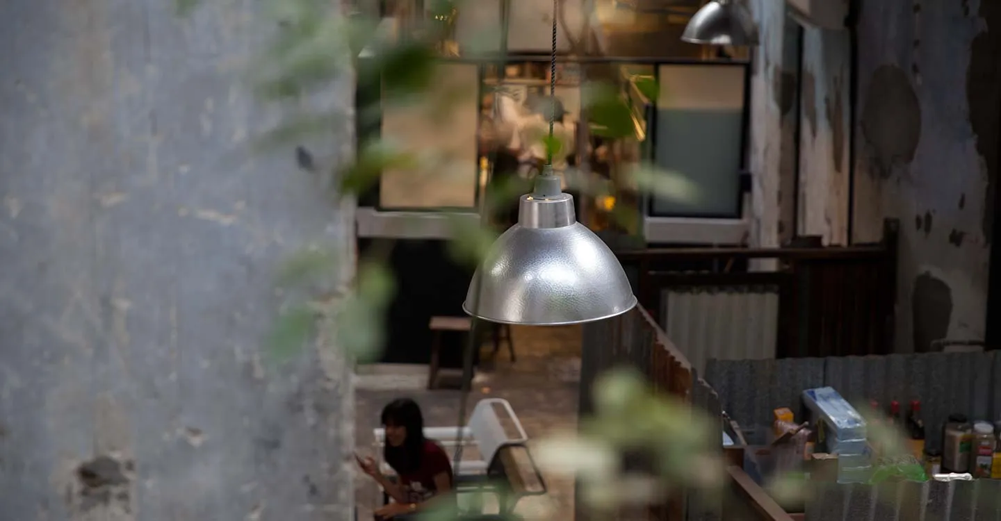 Industrial-style restaurant with metallic pendant lights hanging from ceiling.