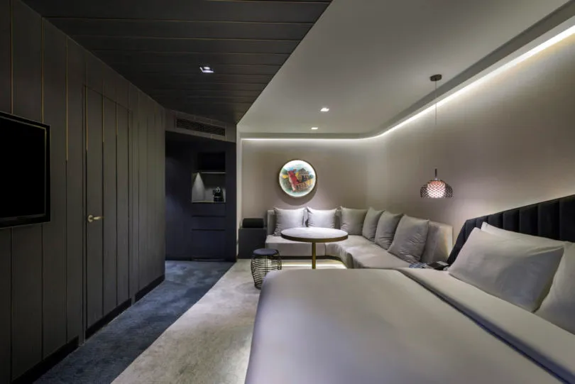 A modern minimalist hotel room featuring concrete flooring and steel accents.
