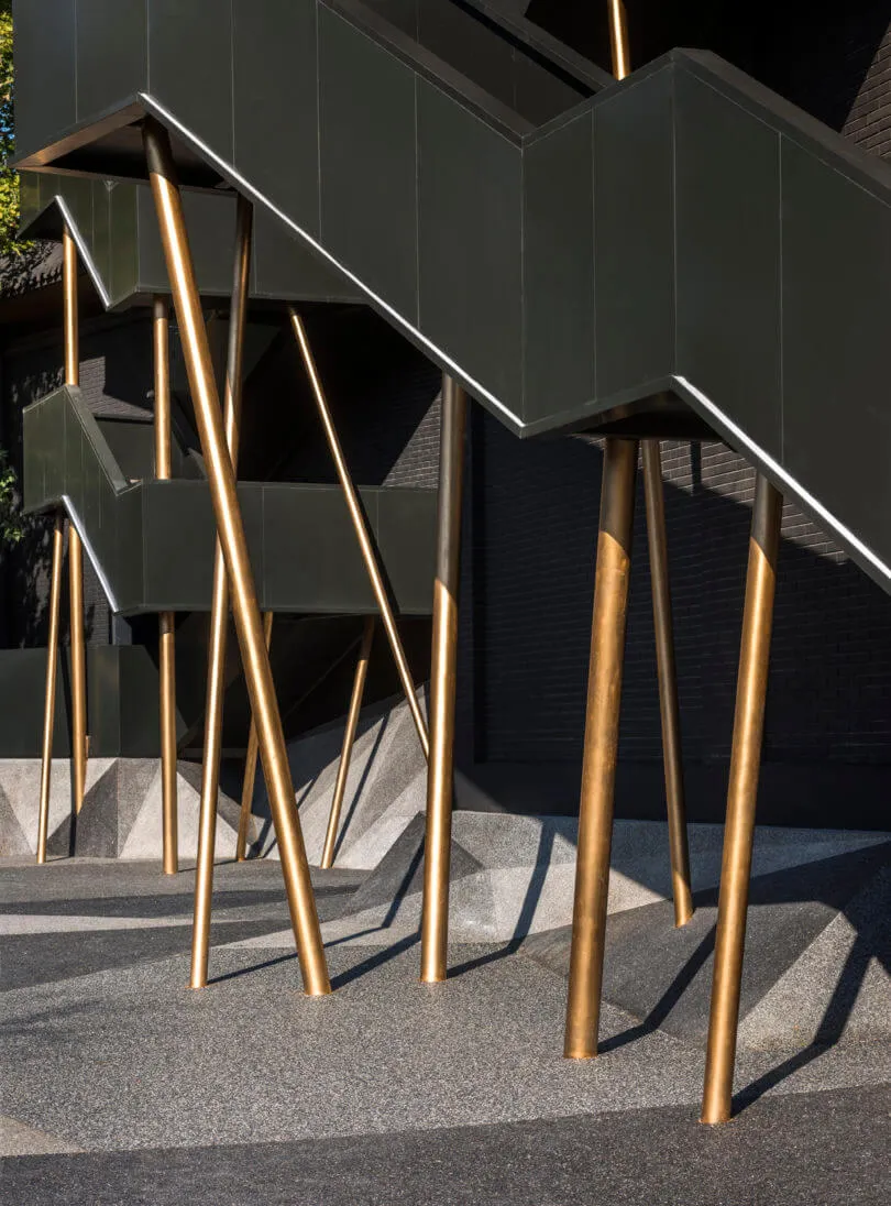 Stairs with gold-colored metal legs and black walls and steps