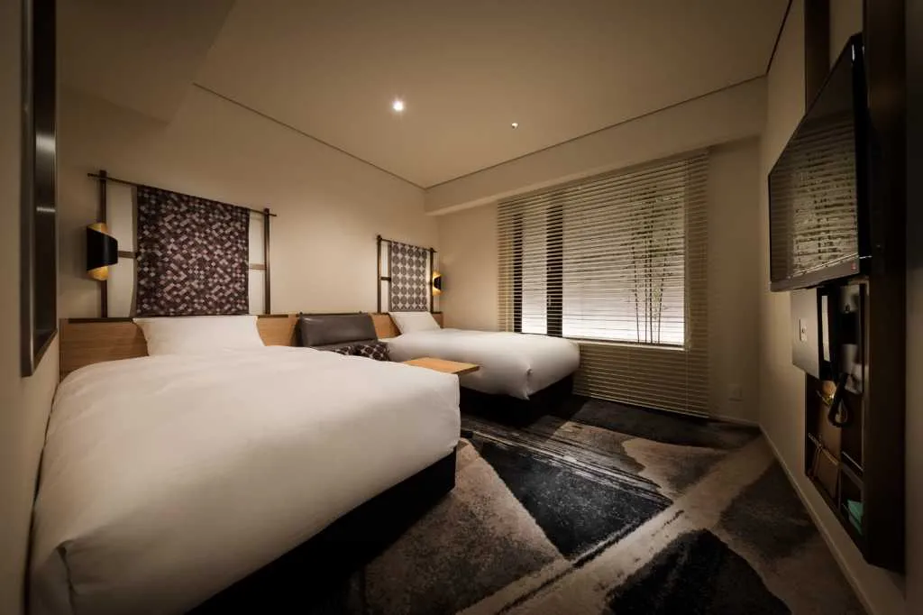 Modern bedroom featuring a cozy feel with textured fabric on the bed, white walls, and hardwood floors.