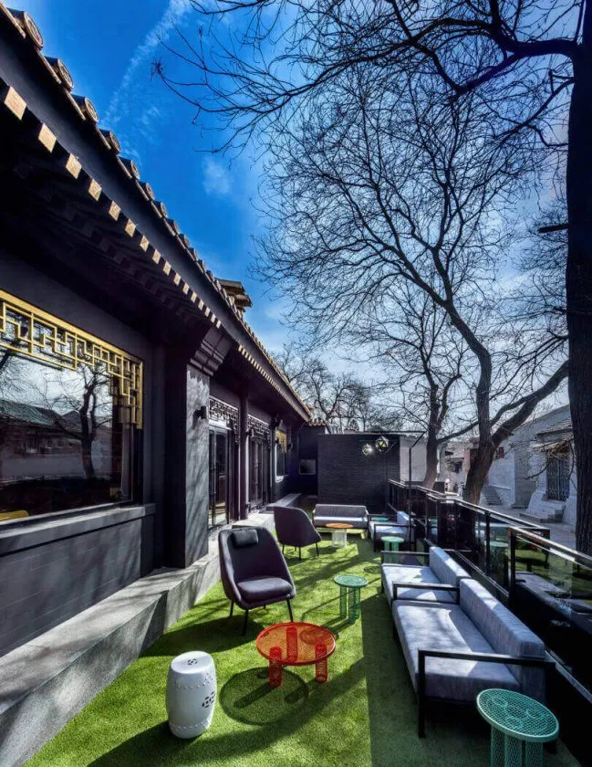 Outdoor balcony with synthetic grass, lounge furniture, and trees in the background