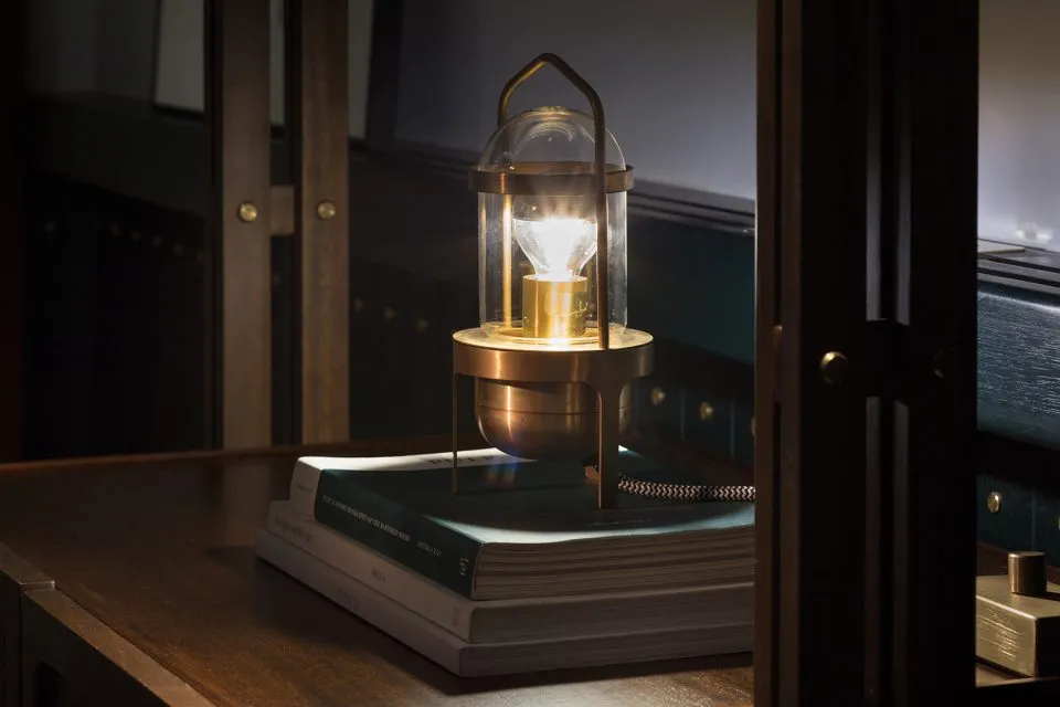 A metal and glass industrial lamp placed on a pile of books.